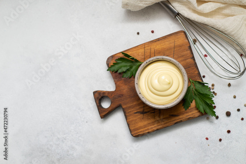 a bowl of mayonnaise with corolla, napkin on the wooden grey background. Copy space. Flat lay.