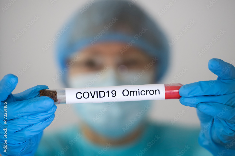 Woman in protective suit holding test tube with sample of analysis suspected to be infected with Omicron variant COVID19 Woman in protective suit holding test tube with sample of analysis suspected to be infected with Omicron variant COVID19