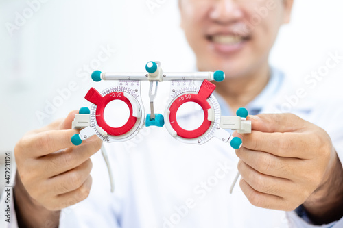 Cropped Optometrist holding adjustable optical trial lenses frame. Eye test and optometry in optical shop concept.