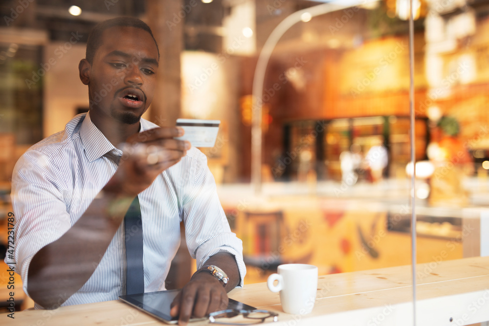 Businessman in cafe holding a credit card. Guy making online payment. Man paying the bill in cafe with a credit card. Businessman in cafe holding a credit card. Guy making online payment. Man paying the bill in cafe with a credit card.