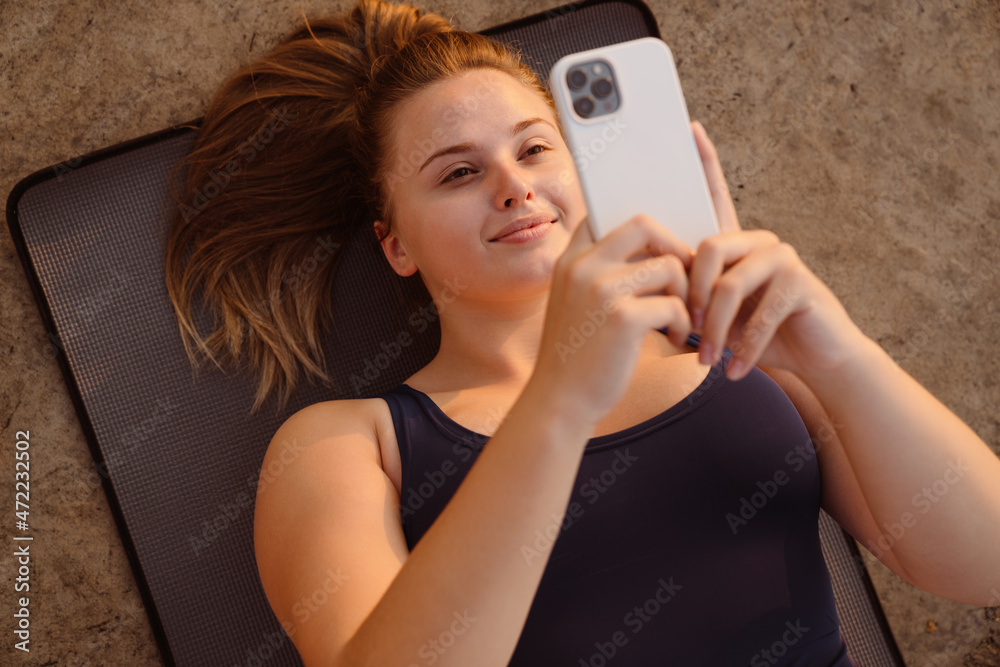 Ginger young woman using cellphone during yoga practice Ginger young woman using cellphone during yoga practice