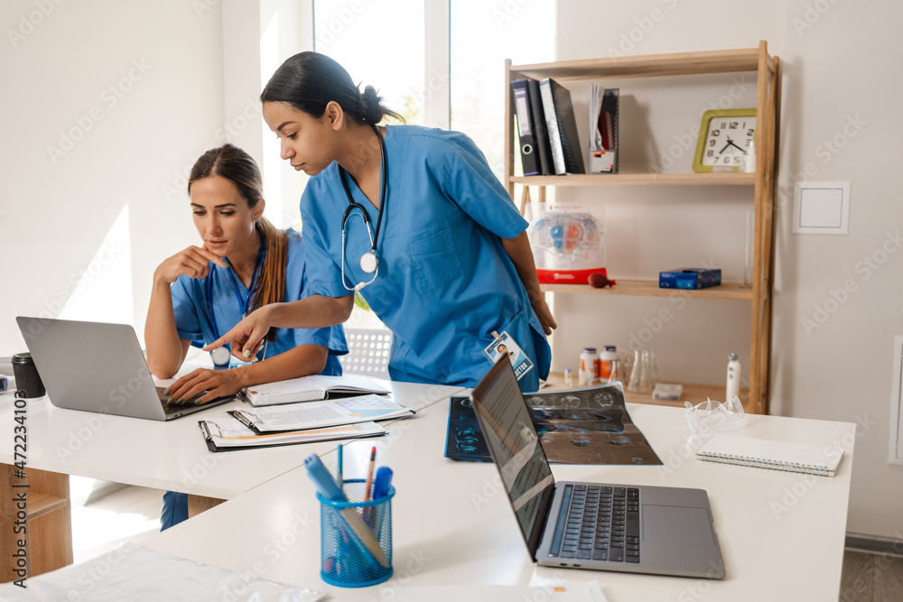 Multiracial women doctors working with laptops in office