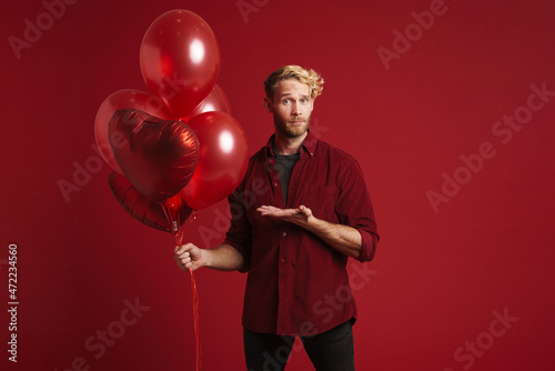 Bearded blonde man holding copyspace while posing with balloons © Drobot Dean