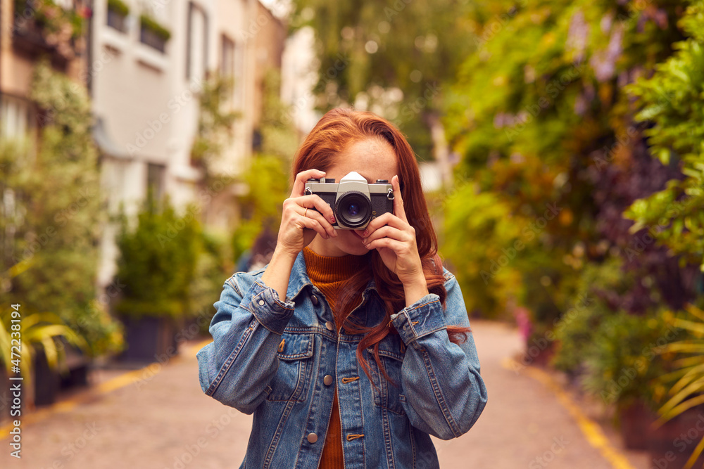 Young Woman In City Taking Photo On Digital Camera To Post To Social Media