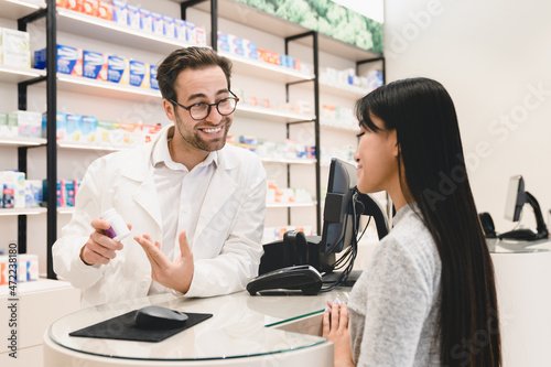 Closeup cropped shot male caucasian pharmacist druggist explaining showing talking advising drugs, painkillers, antibiotics, consulting female customer client buyer in pharmacy drugstore