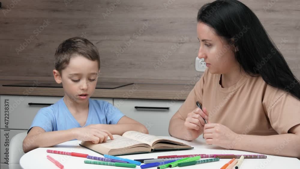 Happy family. Mom and son on home education. Distance education. Mom or teacher teaches her son to read. The concept of private education. A child is reading a book. Happy family. Mom and son on home education. Distance education. Mom or teacher teaches her son to read. The concept of private education. A child is reading a book.