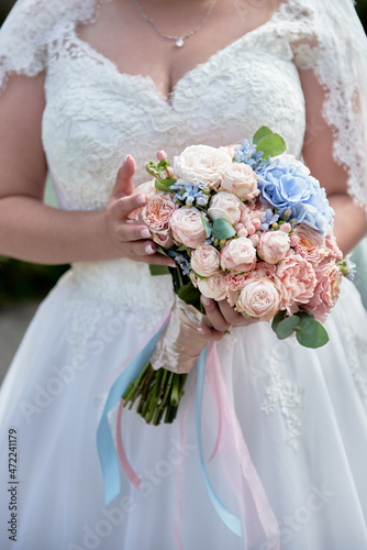 Portrait of beautiful bride in wedding dress with bridal bouquet of white and pink rose flowers outdoors, copy space. Wedding concept