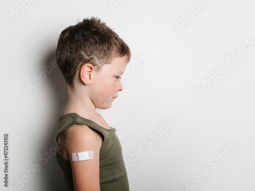 Schoolboy after vaccination with band aid on arm photo