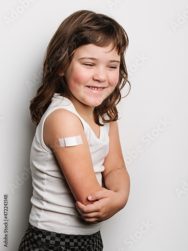 Happy vaccinated girl with band aid on arm