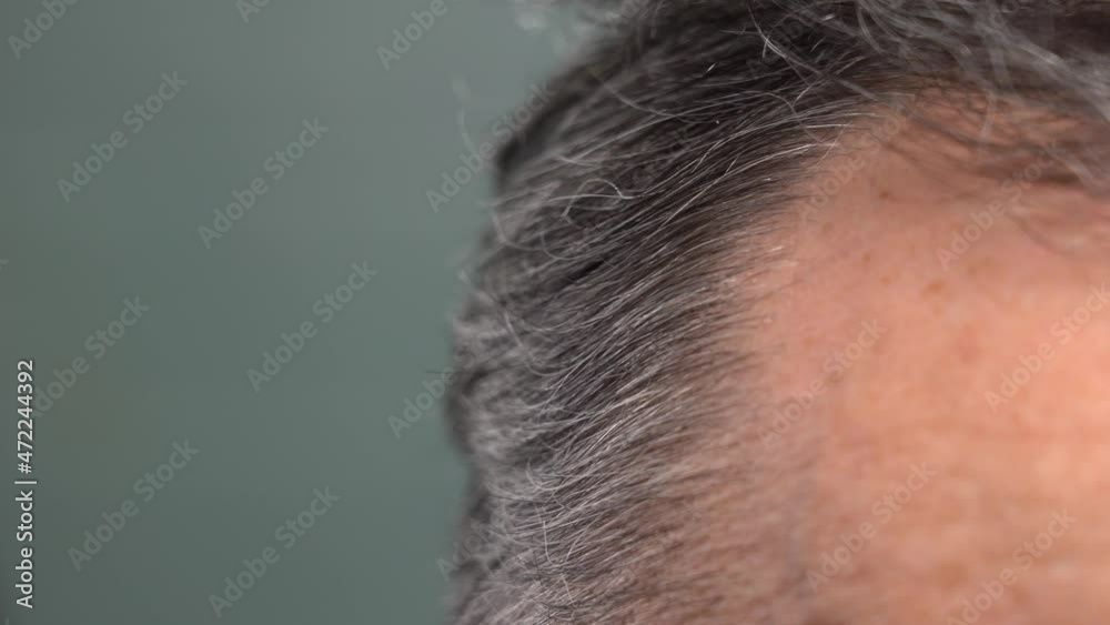 an elderly man runs his hand through his gray hair. aging concept. close-up. side view an elderly man runs his hand through his gray hair. aging concept. close-up. side view