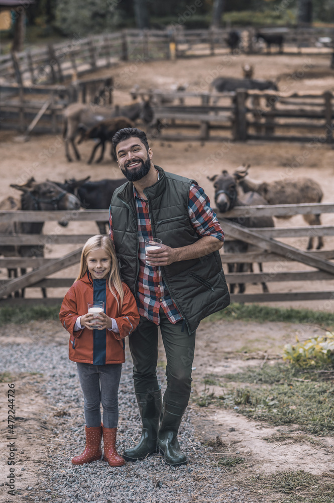 A blonde girl and her father holding a glass of organic milk