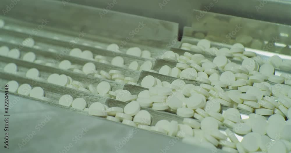 modern pharmaceutical production.white round tablets move on the production line.technological process close-up. modern pharmaceutical production.white round tablets move on the production line.technological process close-up.