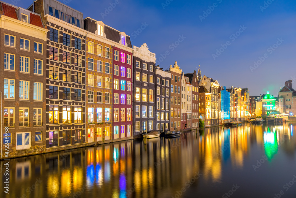 Panoramic view of Famous old houses of Amsterdam. The houses stand in the water and have a beautiful reflection at night. Touristic district Damrak. These houses are famous all over the world.