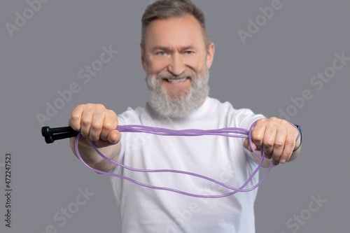 A smiling positive man with a jump rope in hands