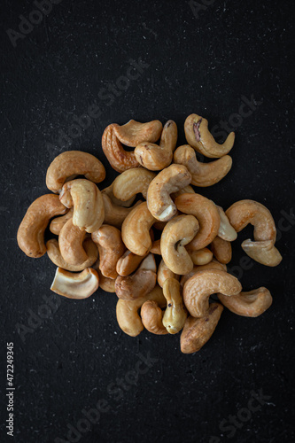 A handful of nuts. Cashew fruit. Asian cuisine. An appetizer for vermouth and beer. Bar food. Appetizing picture. Fried cashews on a black background. A healthy snack.