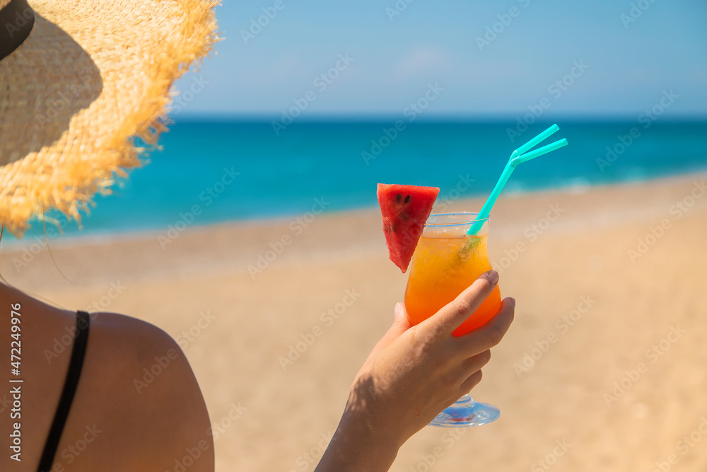A woman holds a cocktail in her hand against the background of the sea. Selective focus. A woman holds a cocktail in her hand against the background of the sea. Selective focus.