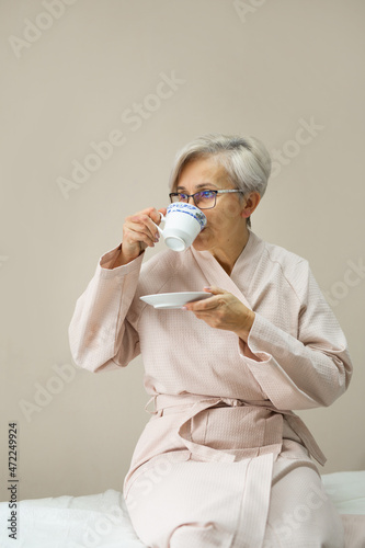 portrait of a stylish aged woman in a robe with a cup of tea 