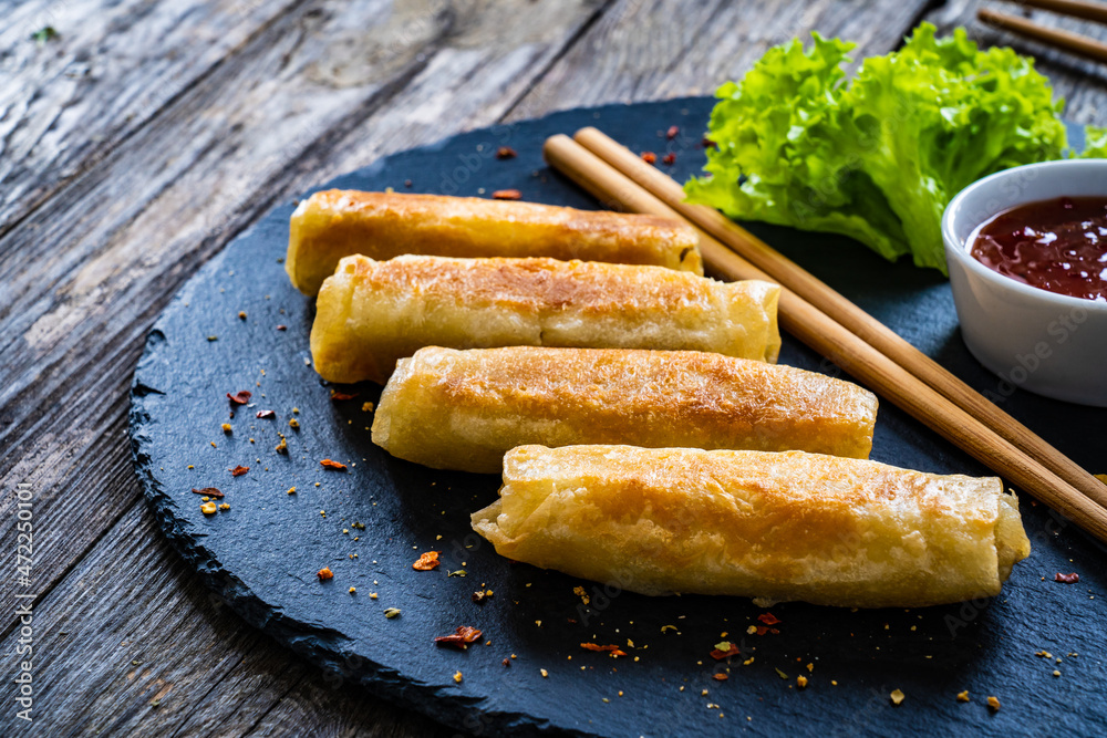 Spring rolls on stone plate on wooden table Spring rolls on stone plate on wooden table