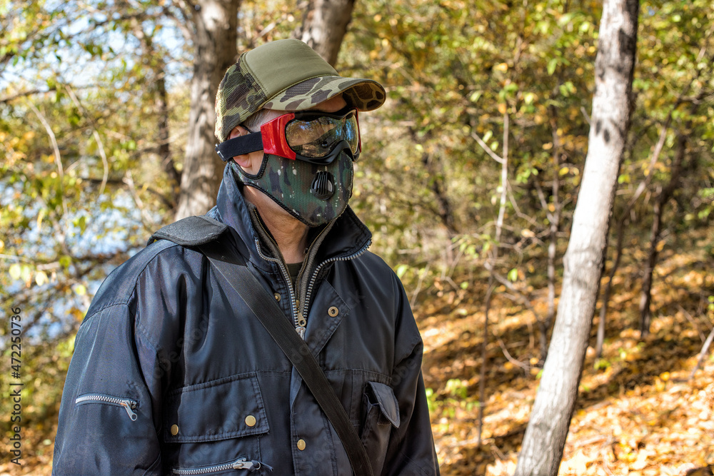 A man wearing respirator mask and protective glasses walking in the forest at COVID-19 period.