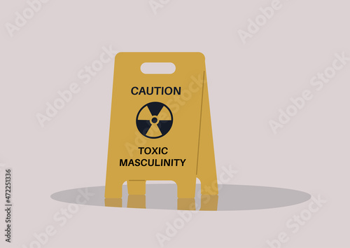 A yellow floor sign warning about toxic masculinity, the idea of manliness as being defined by domination, homophobia, and aggression