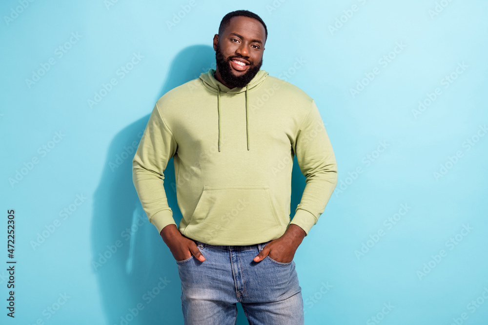 Photo of glad friendly person put hands in pockets beaming smile look camera isolated on blue color background Photo of glad friendly person put hands in pockets beaming smile look camera isolated on blue color background