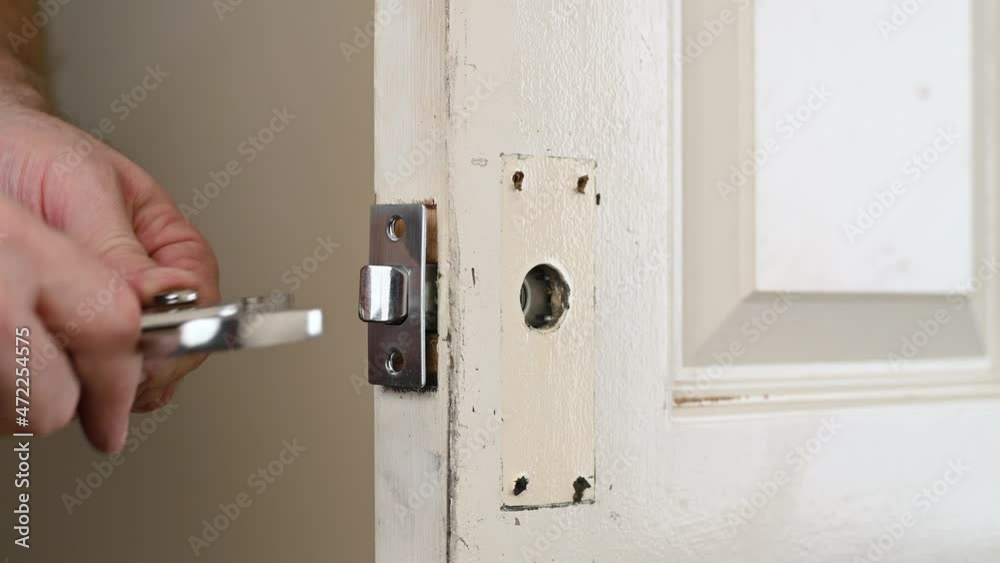 A man's hands use pliers to remove a door lock A man's hands use pliers to remove a door lock