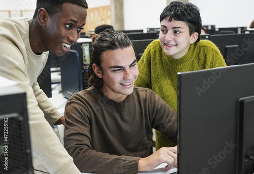 Young diverse students learning together inside computer class room