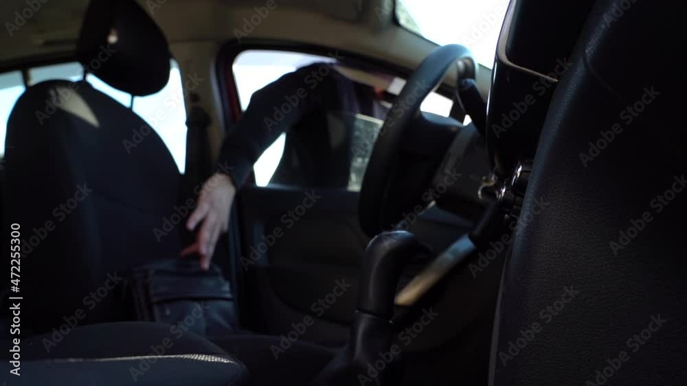 a man in a black hoodie and black glasses steals a bag from the seat of someone else's car. transportation, crime and ownership concept a man in a black hoodie and black glasses steals a bag from the seat of someone else's car. transportation, crime and ownership concept