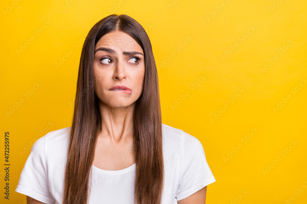 Photo portrait girl brown hair white t-shirt looking copyspace biting lip isolated vivid yellow color background Photo portrait girl brown hair white t-shirt looking copyspace biting lip isolated vivid yellow color background