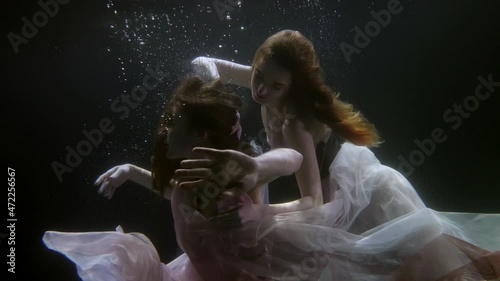 mysterious lesbians under the water in dresses swim like fabulous mermaids