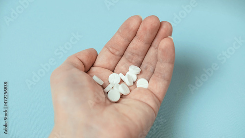 white pills in hand on a blue background , the concept of Christmas and medicine