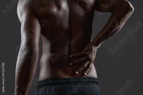 Athletic black man touching his back with backache