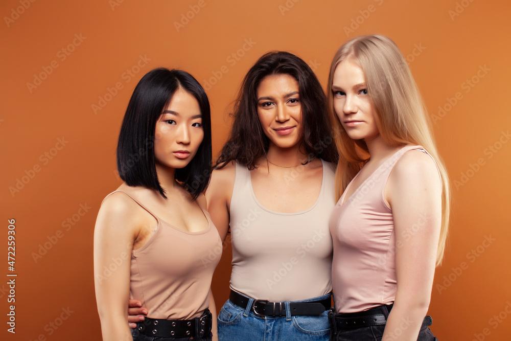 young pretty asian, caucasian, african woman posing cheerful together on brown background, lifestyle diverse nationality people concept young pretty asian, caucasian, african woman posing cheerful together on brown background, lifestyle diverse nationality people concept