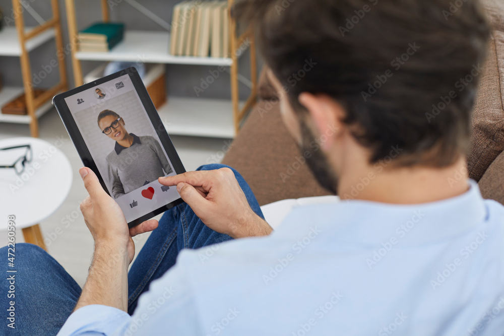 Man on digital tablet looks at profile photo of attractive young woman in dating app and presses red heart like button. Concept of finding love online. Close-up, selective focus. Man on digital tablet looks at profile photo of attractive young woman in dating app and presses red heart like button. Concept of finding love online. Close-up, selective focus.