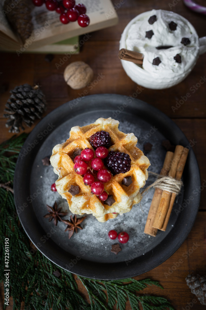 
Waffles with blackberries and currants. Christmas sweets. Table with desserts and Christmas decorations. Still life with sweets