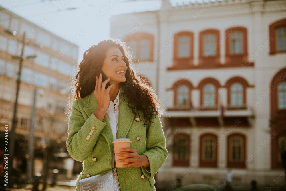 Young woman using smartphone on the street and holding takeaway coffee Young woman using smartphone on the street and holding takeaway coffee