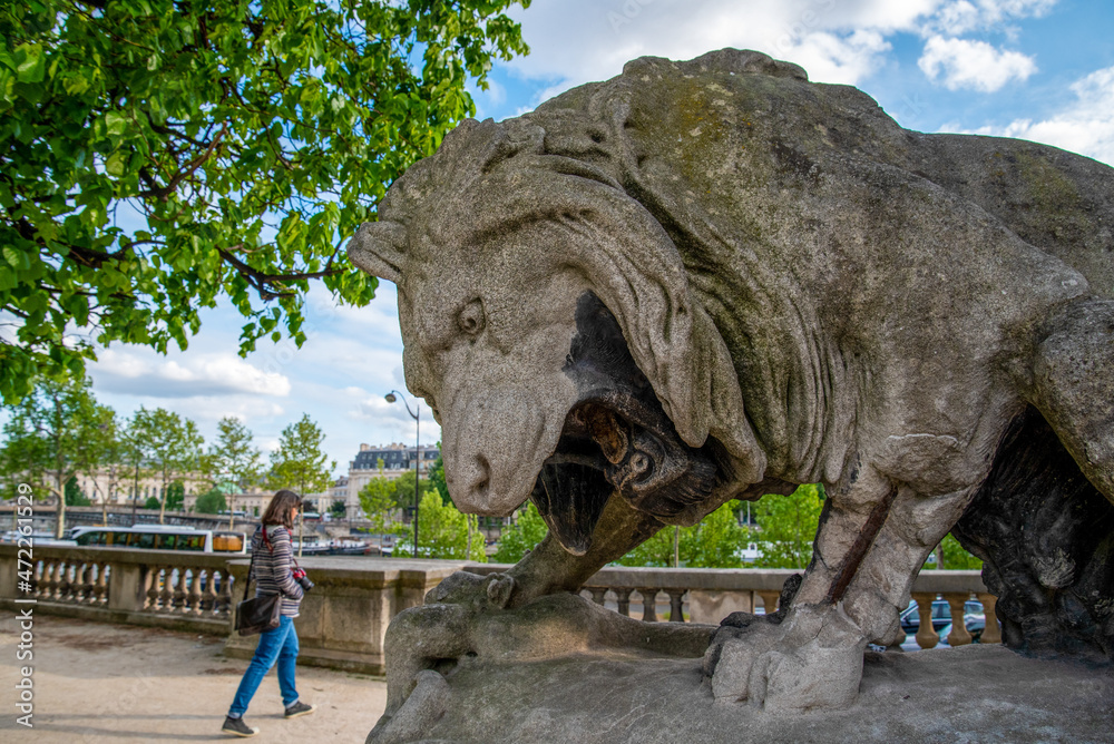 Fototapeta premium Giant lion sculpture roaring at a Person walking by, Park of Louvre Palace in Paris