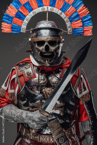 Screaming evil zombie centurion with sword isolated on gray photo