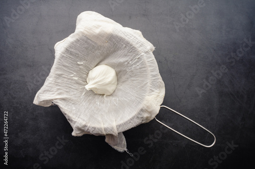 Freshly Made Labneh Cheese in a Cheesecloth Lined Strainer: Freshly pressed yogurt cheese viewed from above photo