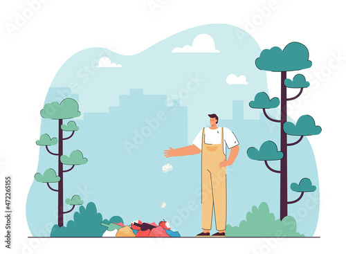 Worker in overall standing near stack of trash in park on city background. Man throwing garbage flat vector illustration. Ecology, environment concept for banner, website design or landing web page