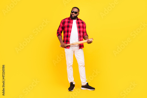 Full size photo of angry aggressive young afro american man hold baseball bat isolated on yellow color background