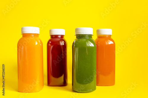 Fresh juices or smoothies of fruits and vegetables in bottles on a yellow background. The concept of a healthy diet, diet or detox. Flat lay, top view