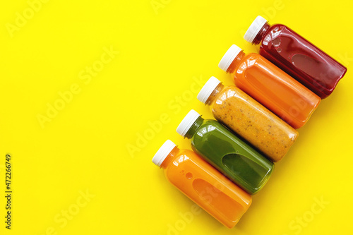 Fresh juices or cocktails of fruits and vegetables in bottles on a yellow background. The concept of a healthy diet or diet. Fresh organic ingredients. Flat lay, top view