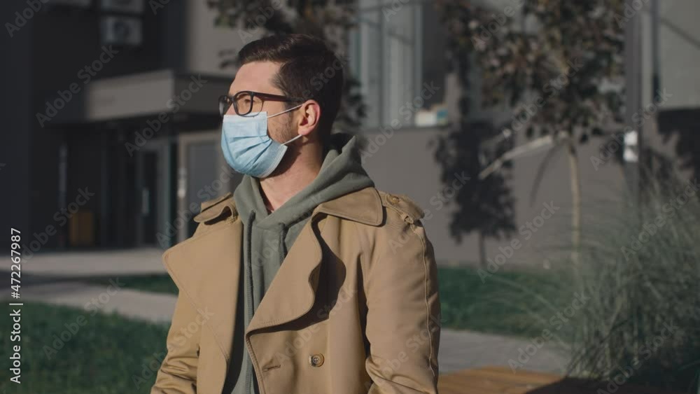 Sick unhealthy young man feeling unwell and sneezing. Ill male suffering from flu or fever and having health problems while standing at the street Sick unhealthy young man feeling unwell and sneezing. Ill male suffering from flu or fever and having health problems while standing at the street