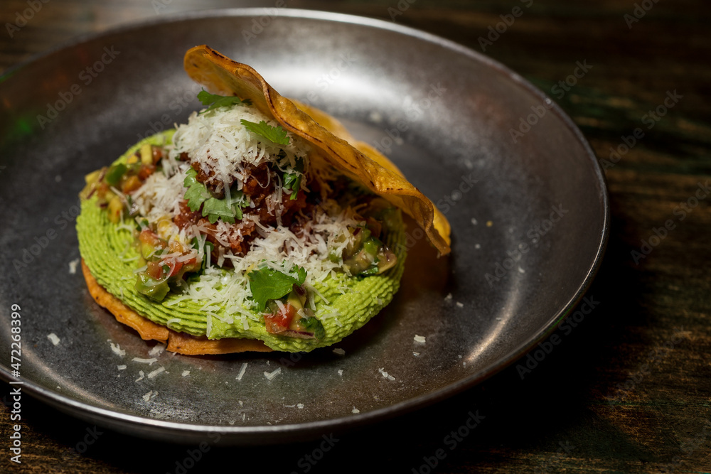 Corn cake or taco stuffed with avocado and different organic vegetables with a lime and cinnamon dressing and cheese sprinkled on top Corn cake or taco stuffed with avocado and different organic vegetables with a lime and cinnamon dressing and cheese sprinkled on top