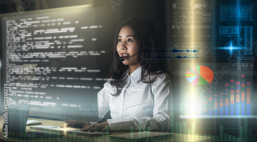 Asian Woman support desk working hard late at night over visual screen of Internet of Things Technology, Call center and customer service with technology and virtual reality concept