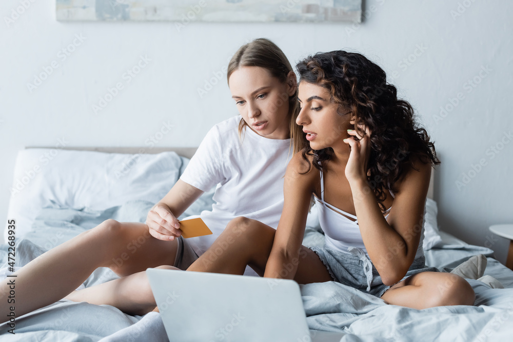 young lesbian couple looking at laptop while online shopping from home young lesbian couple looking at laptop while online shopping from home
