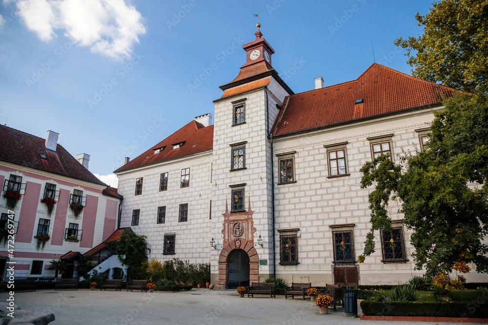 Trebon, South Bohemia, Czech Republic, 9 October 2021: Castle Courtyard, Renaissance chateau with tower and sgraffito mural decorated plaster at facade at sunny day, medieval historical town with park