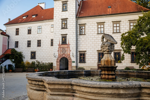 Trebon, South Bohemia, Czech Republic, 9 October 2021: Castle Courtyard, Renaissance chateau with sgraffito mural decorated plaster at facade, fountain with sculpture of bird perched on three heads
