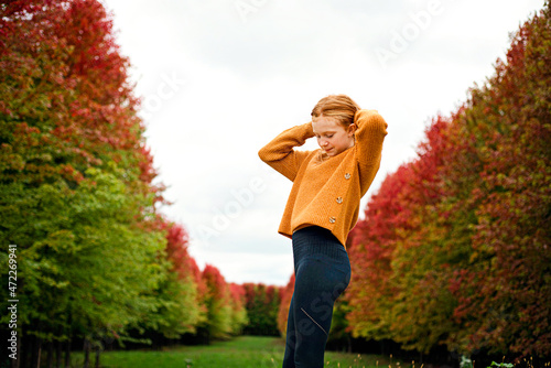 Happy tween girl surrounded by fall color trees. photo